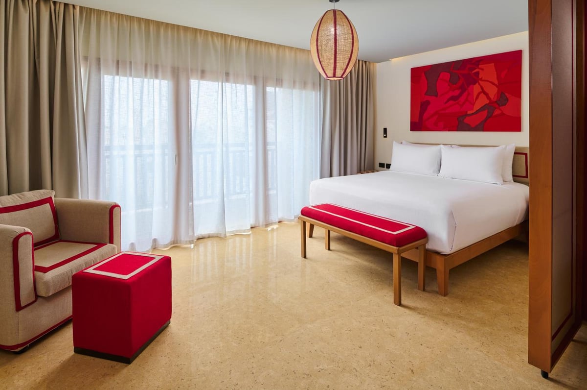 Steigenberger Aldau Beach Hotel guest bedroom with a white bed and floor-to-ceiling curtains.