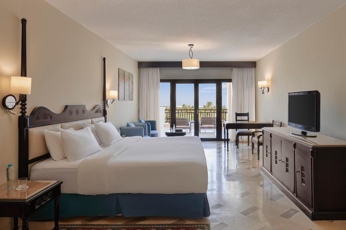 Steigenberger Aldau Beach Hotel guest room with a large bed and balcony doors.