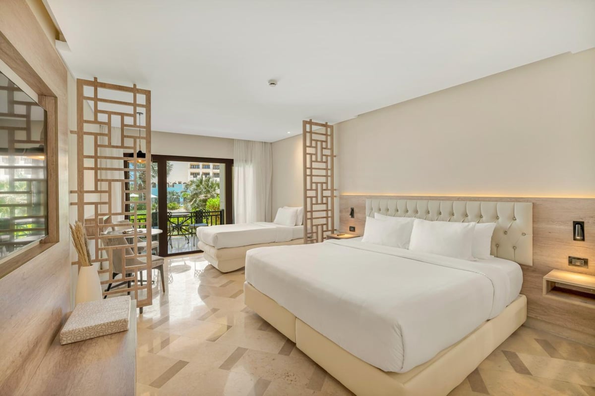 Steigenberger Aldau Beach Hotel guest room with a large bed and sitting area.