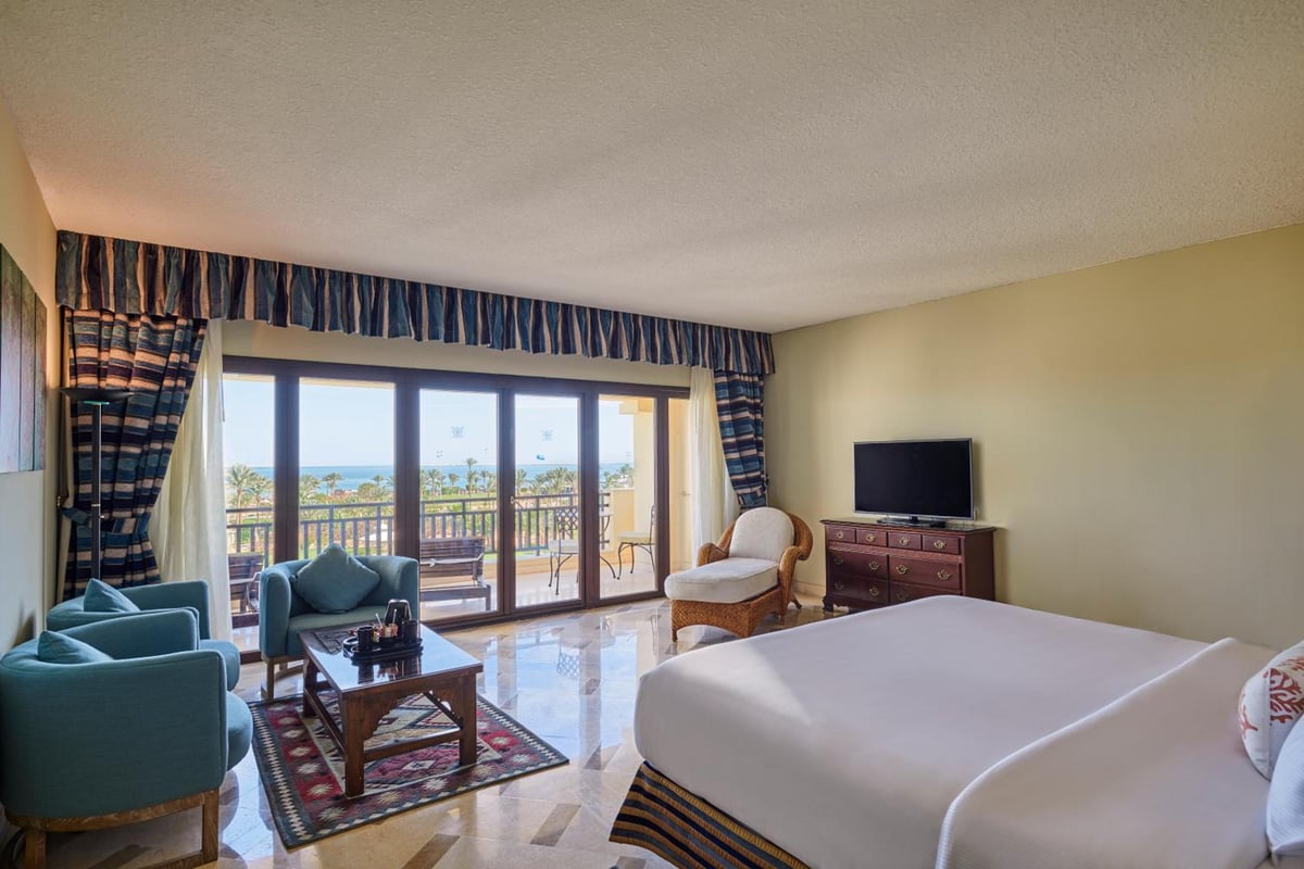 Steigenberger Aldau Beach Hotel bedroom with a large bed and balcony doors.