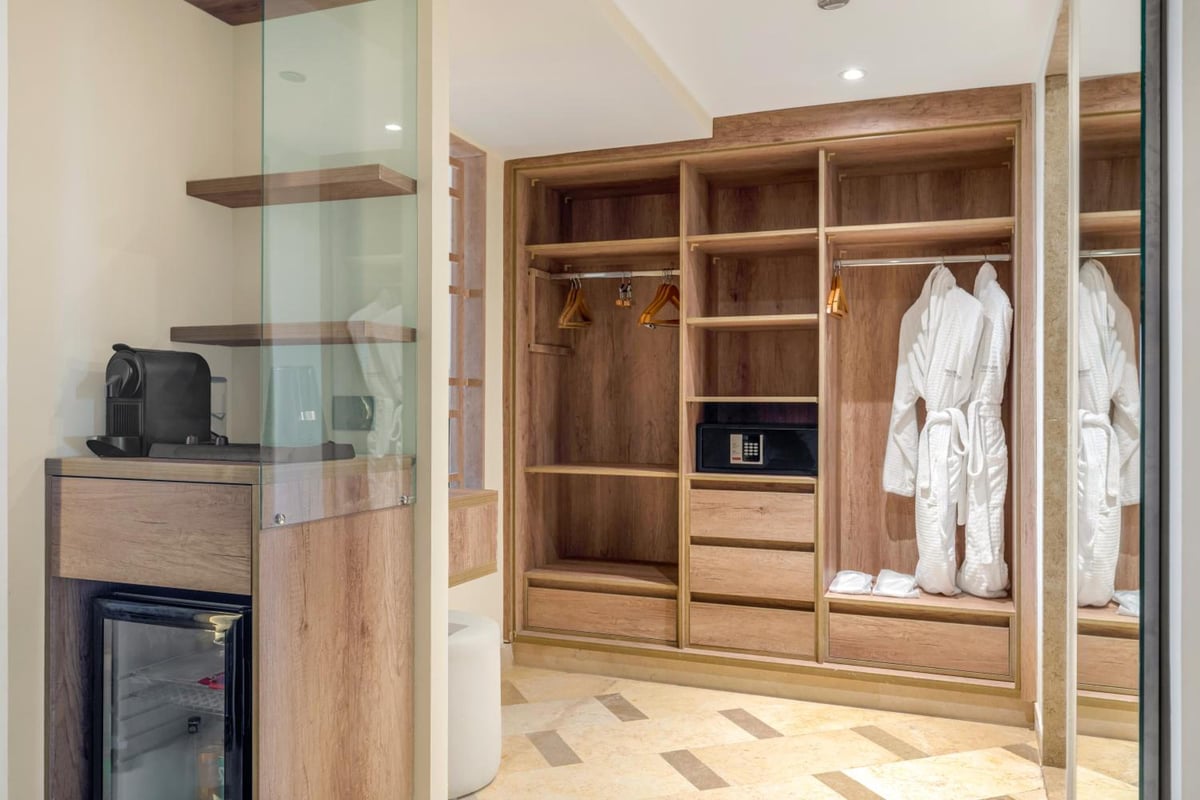 Steigenberger Aldau Beach Hotel walk-in wardrobe with wooden shelving and hanging robes.