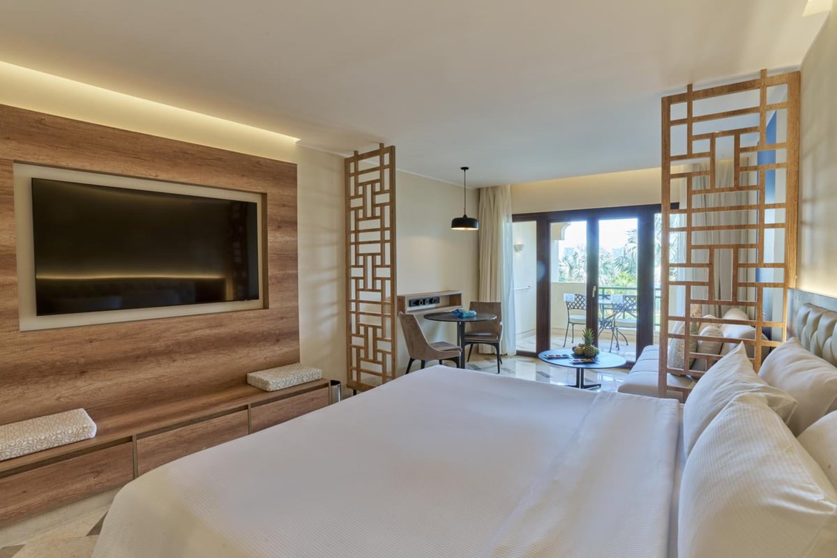 Steigenberger Aldau Beach Hotel bedroom with a large bed and wooden lattice screens.