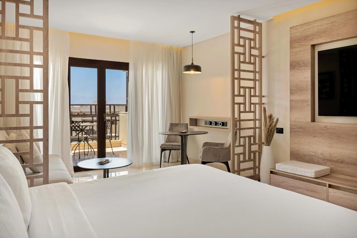 Steigenberger Aldau Beach Hotel guest room with a white bed and balcony doors.
