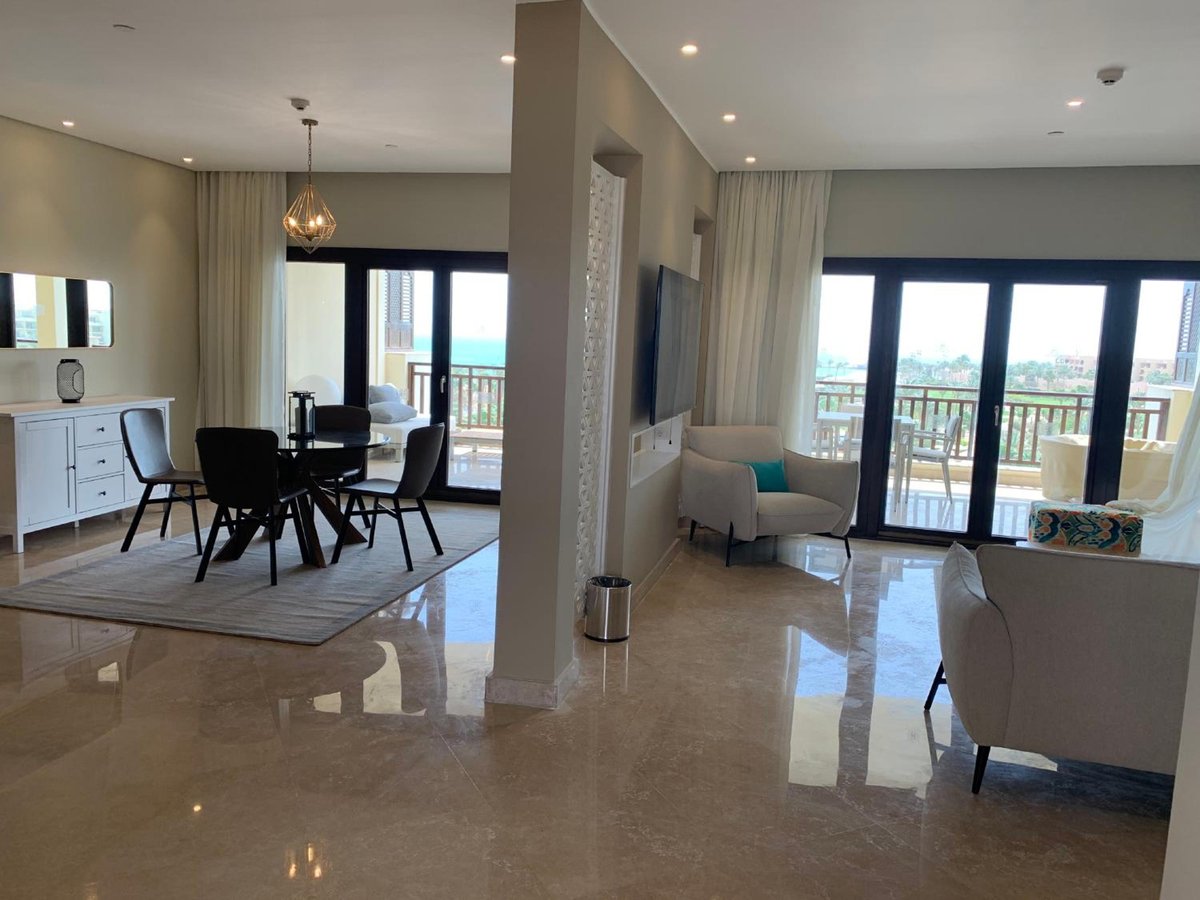 Steigenberger Aldau Beach Hotel suite living area with a dining area and balcony doors.