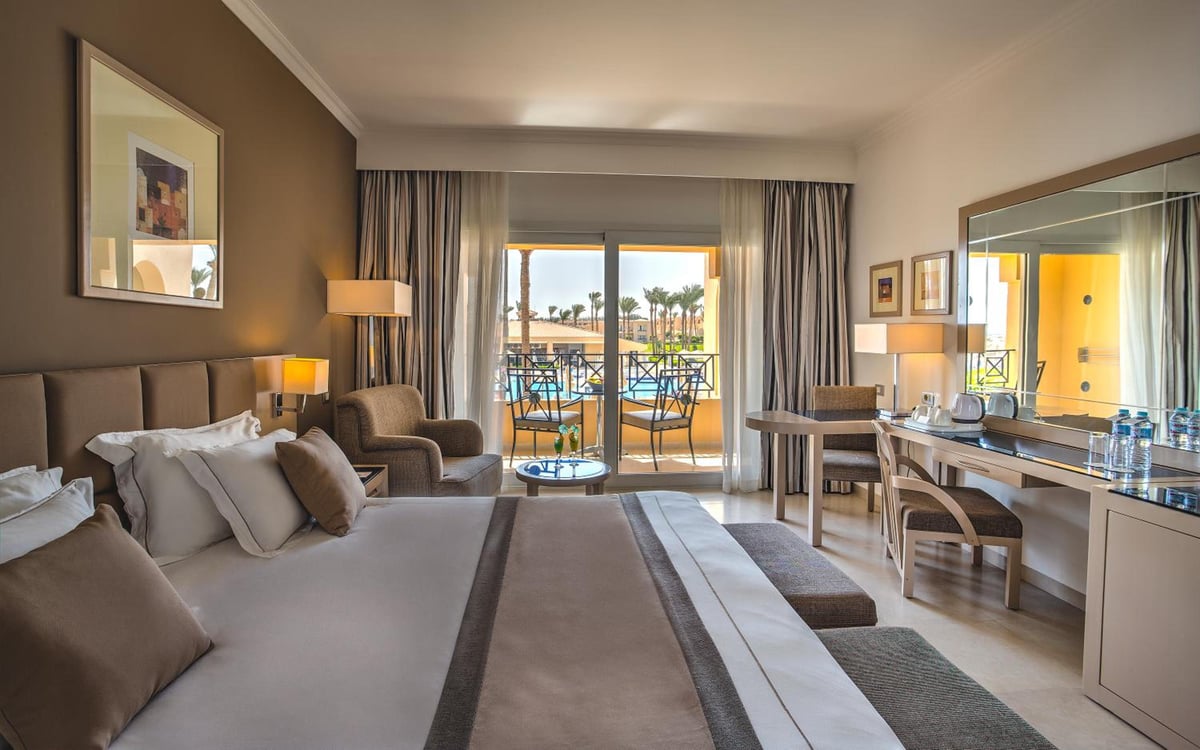 Cleopatra Luxury Resort Makadi Bay guest room with a large bed and balcony doors.