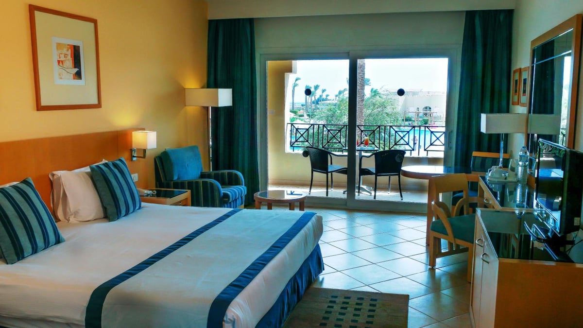 Cleopatra Luxury Resort Makadi Bay guest bedroom with a large bed and glass balcony doors.