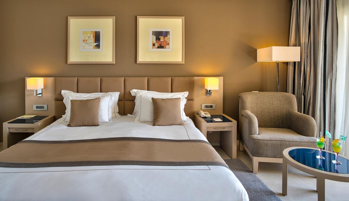 Cleopatra Luxury Resort Makadi Bay guest bedroom with a made bed and an armchair.