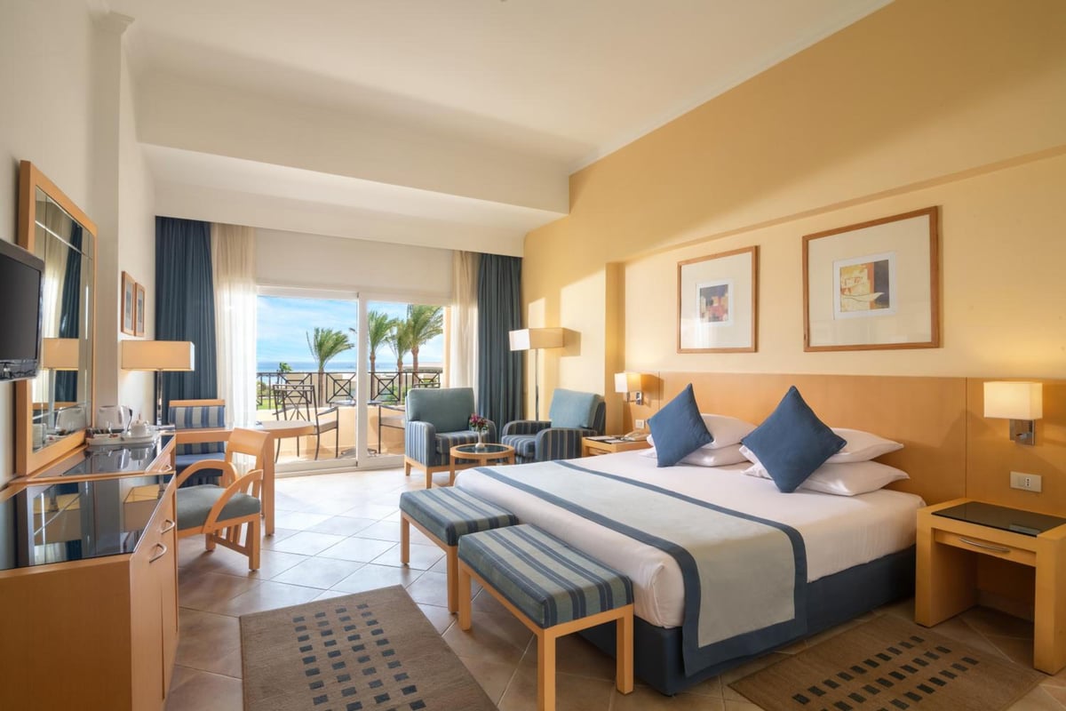 Cleopatra Luxury Resort Makadi Bay guest bedroom with a large bed and balcony doors.
