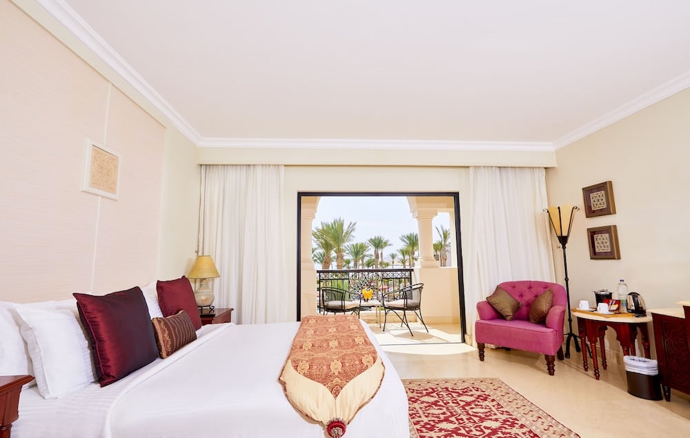 Pickalbatros The Palace Port Ghalib bedroom with a white bed and balcony seating area.