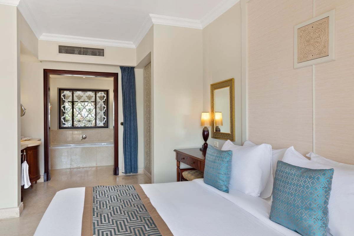 Pickalbatros The Palace Port Ghalib bedroom with a white bed and blue accent pillows.