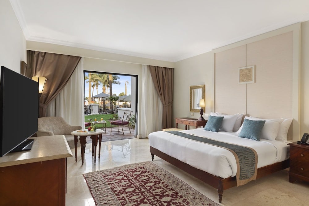 Pickalbatros The Palace Port Ghalib bedroom with a large bed and sliding glass doors.