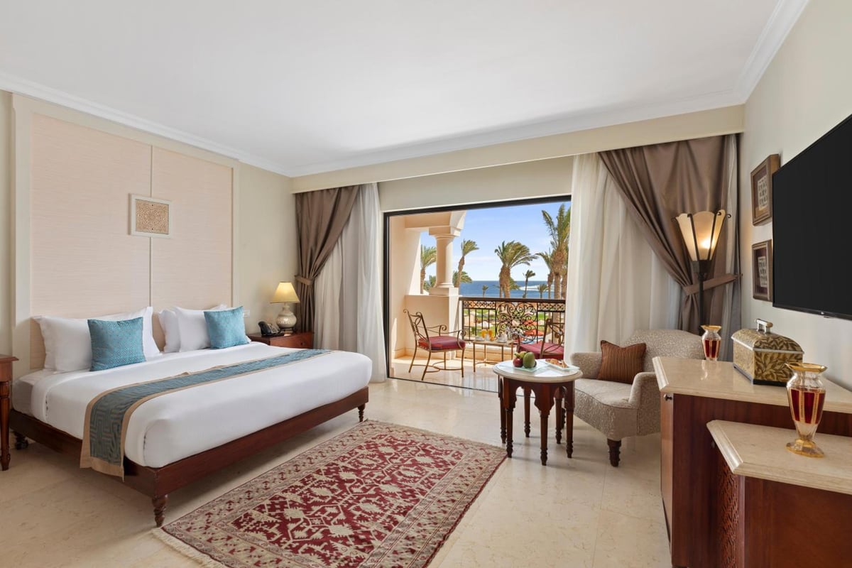 Pickalbatros The Palace Port Ghalib bedroom with a bed and balcony overlooking the water.