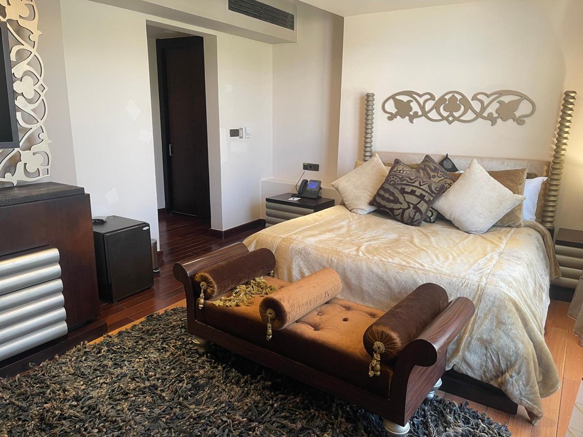 Pickalbatros The Palace Port Ghalib bedroom with a gold bedspread and carved headboard.