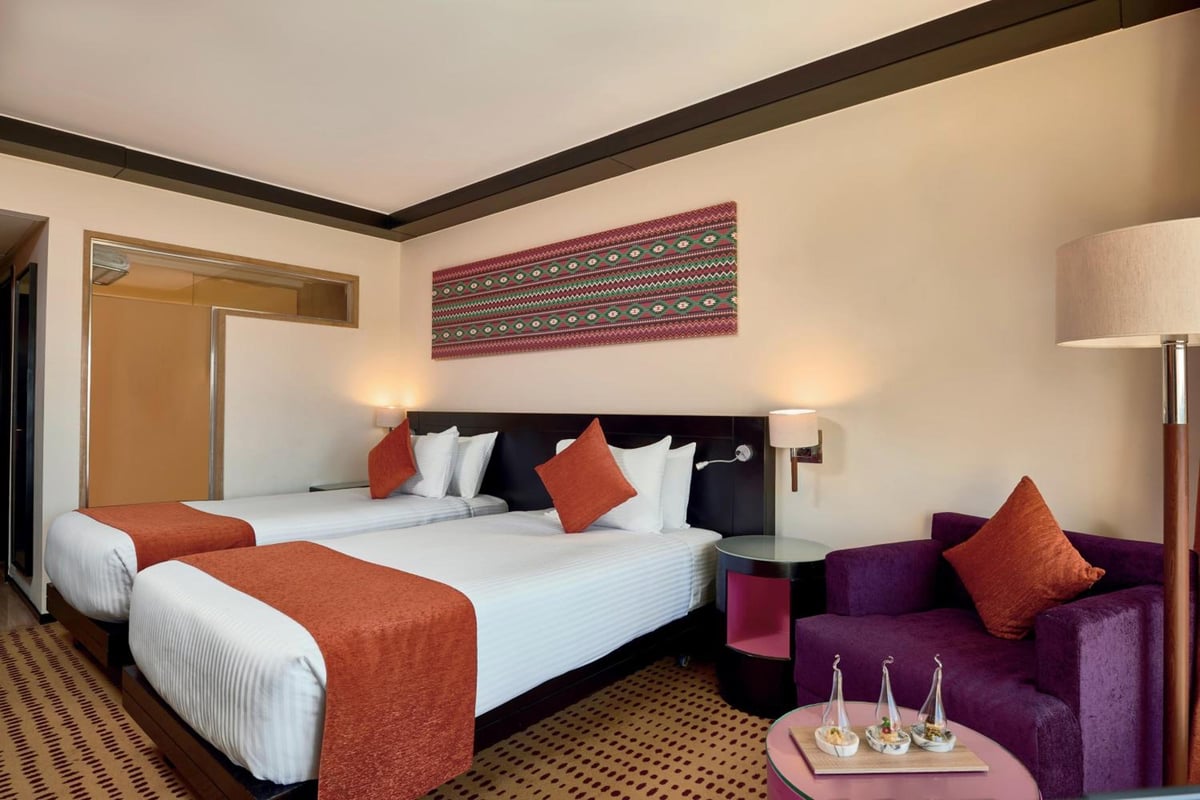 Movenpick Resort Aswan twin bedroom with two beds and a purple armchair.