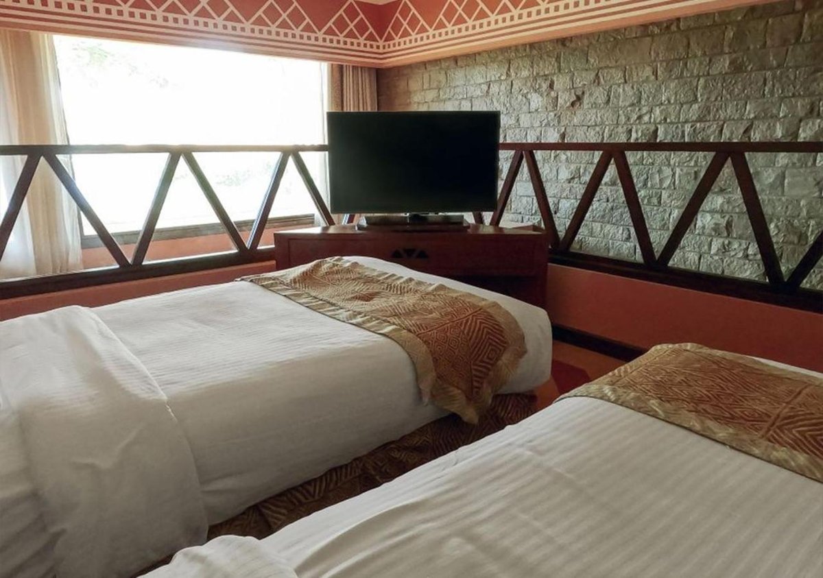 Movenpick Resort Aswan guest room with two beds and stone walls.