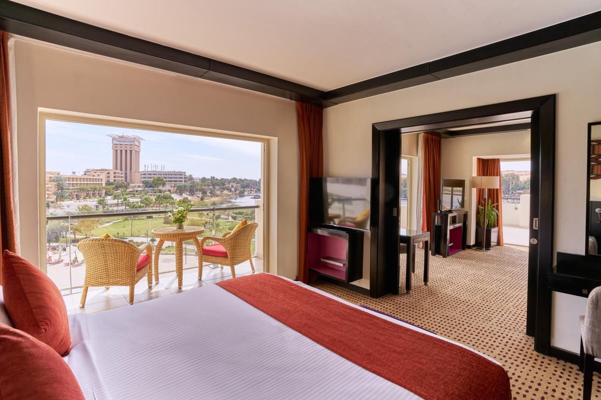 Movenpick Resort Aswan suite bedroom with a balcony and adjoining sitting area.
