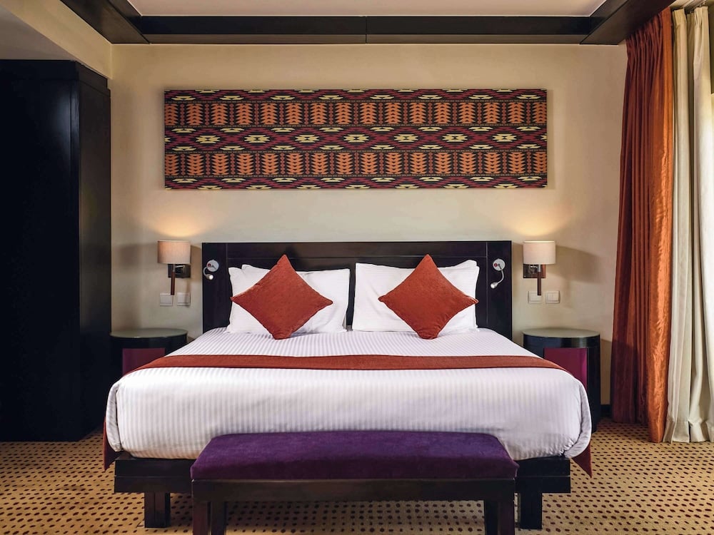 Movenpick Resort Aswan bedroom with a bed and patterned wall art.