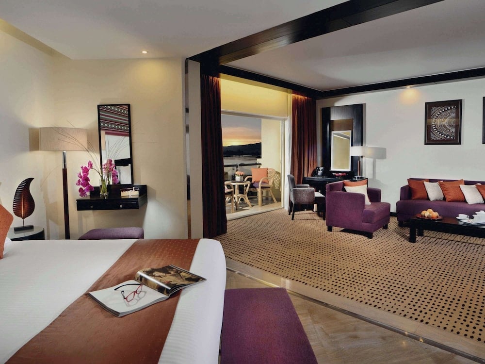 Movenpick Resort Aswan suite with a bed and a separate sitting area.