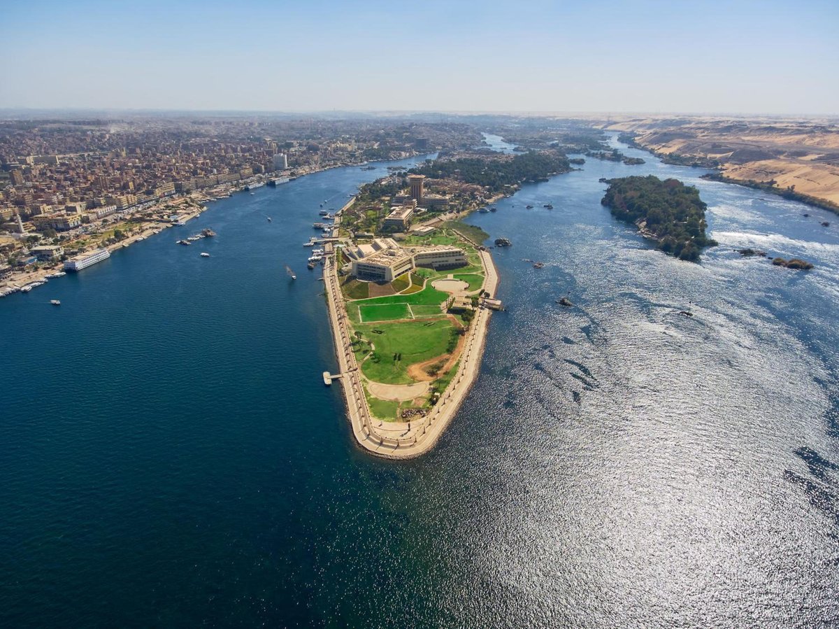 Movenpick Resort Aswan island grounds with green lawns and surrounding Nile water.