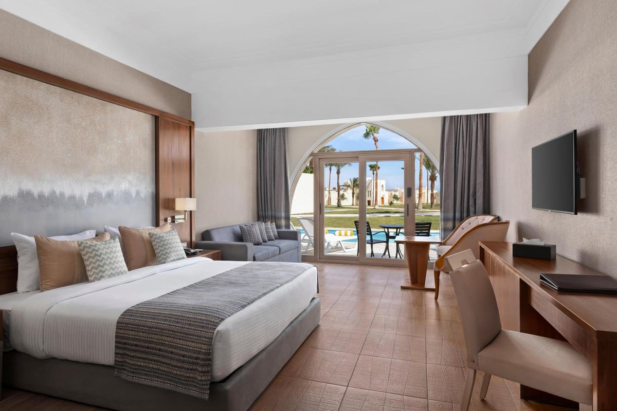 Xanadu Makadi Bay guest room with a bed and arched glass doors.