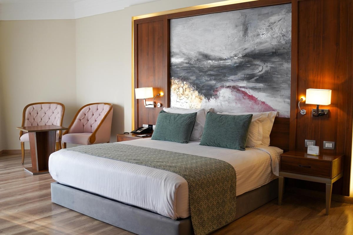 Xanadu Makadi Bay guest room with a large bed and abstract wall art.