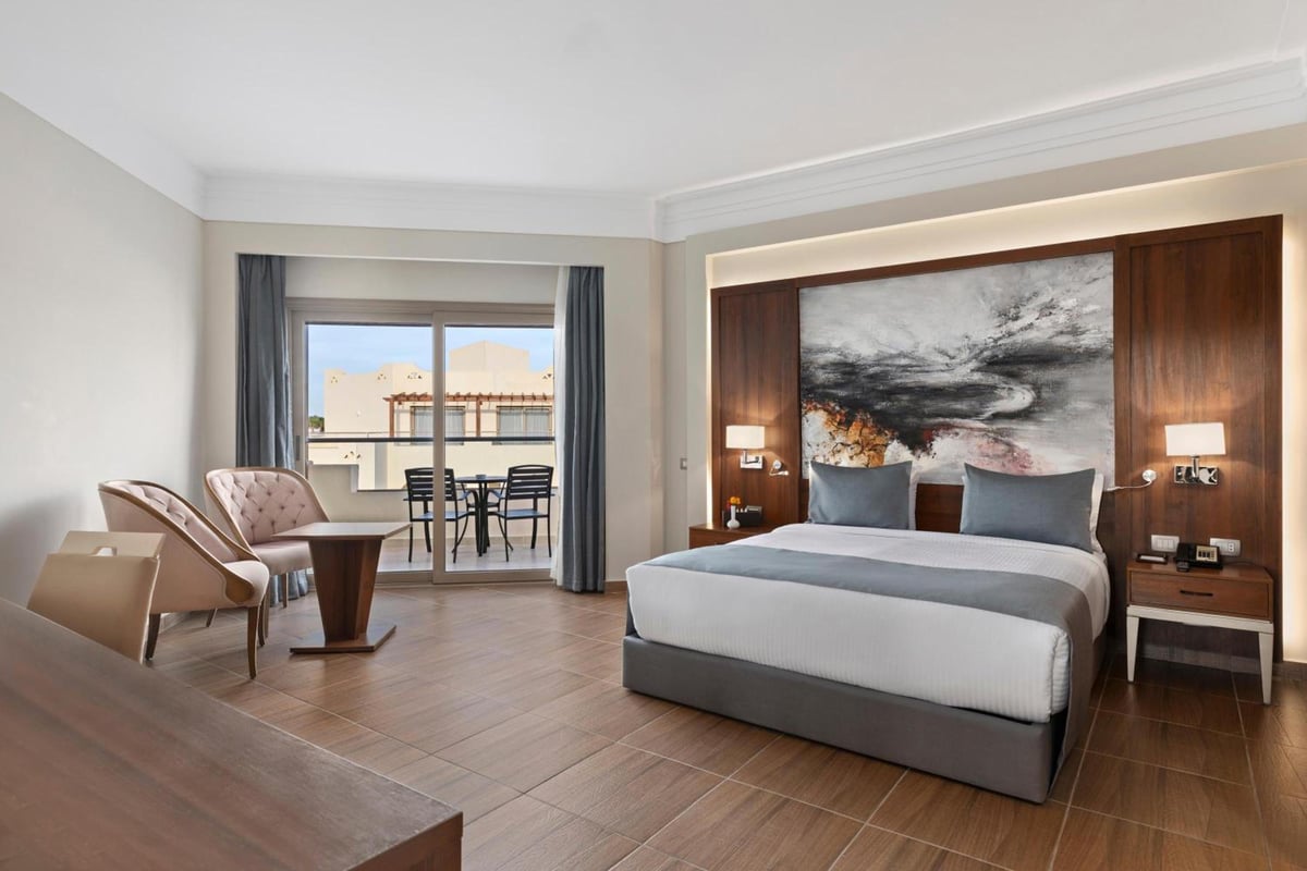 Xanadu Makadi Bay guest room with a large bed and glass balcony doors.