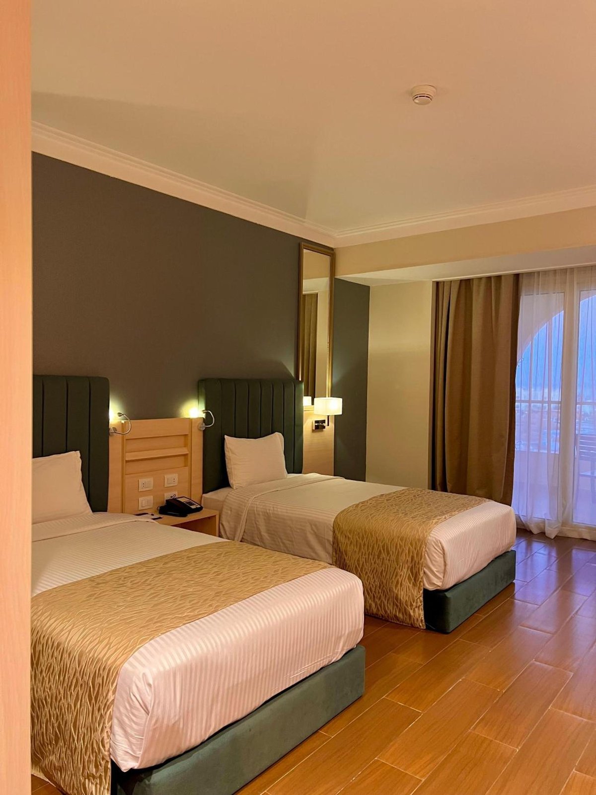 Xanadu Makadi Bay twin bedroom with two beds and curtained glass doors.