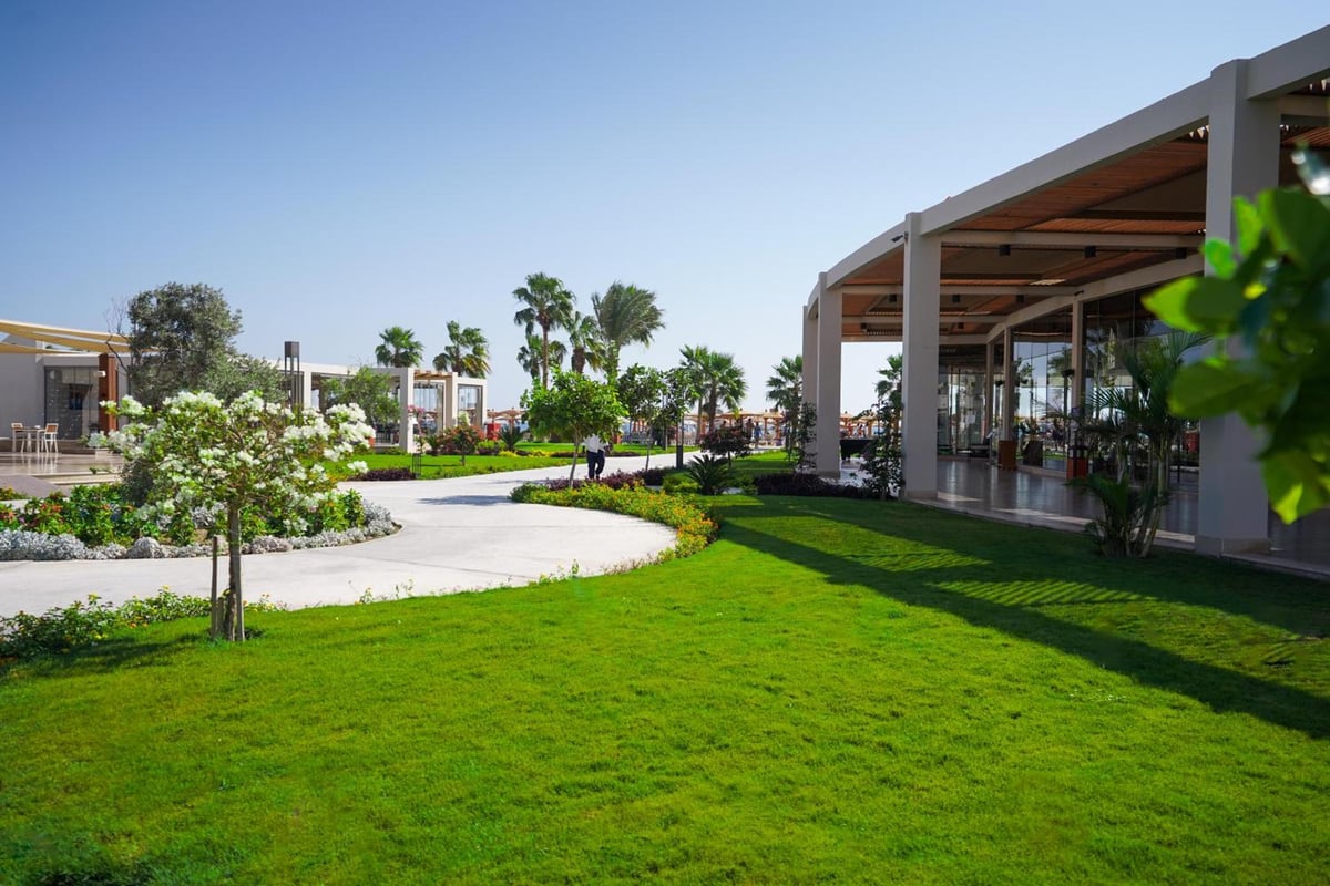 Xanadu Makadi Bay garden grounds with a green lawn and glass-fronted pavilion.