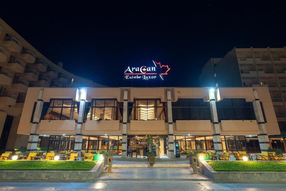 Aracan Eatabe Luxor Hotel exterior with lit sign and outside seating.