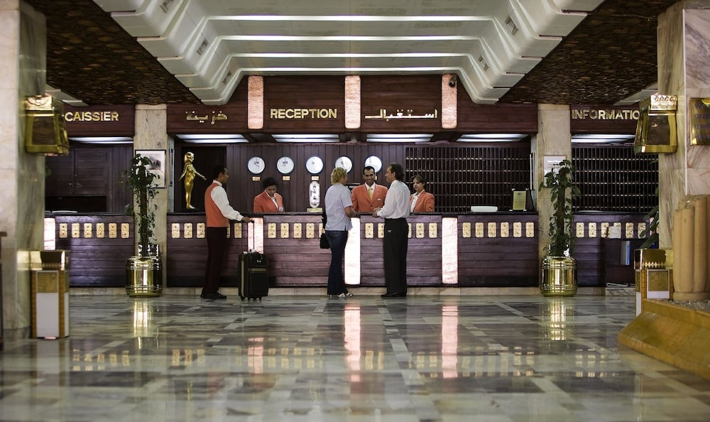 Aracan Eatabe Luxor Hotel reception desk with marble flooring and long wooden counter.