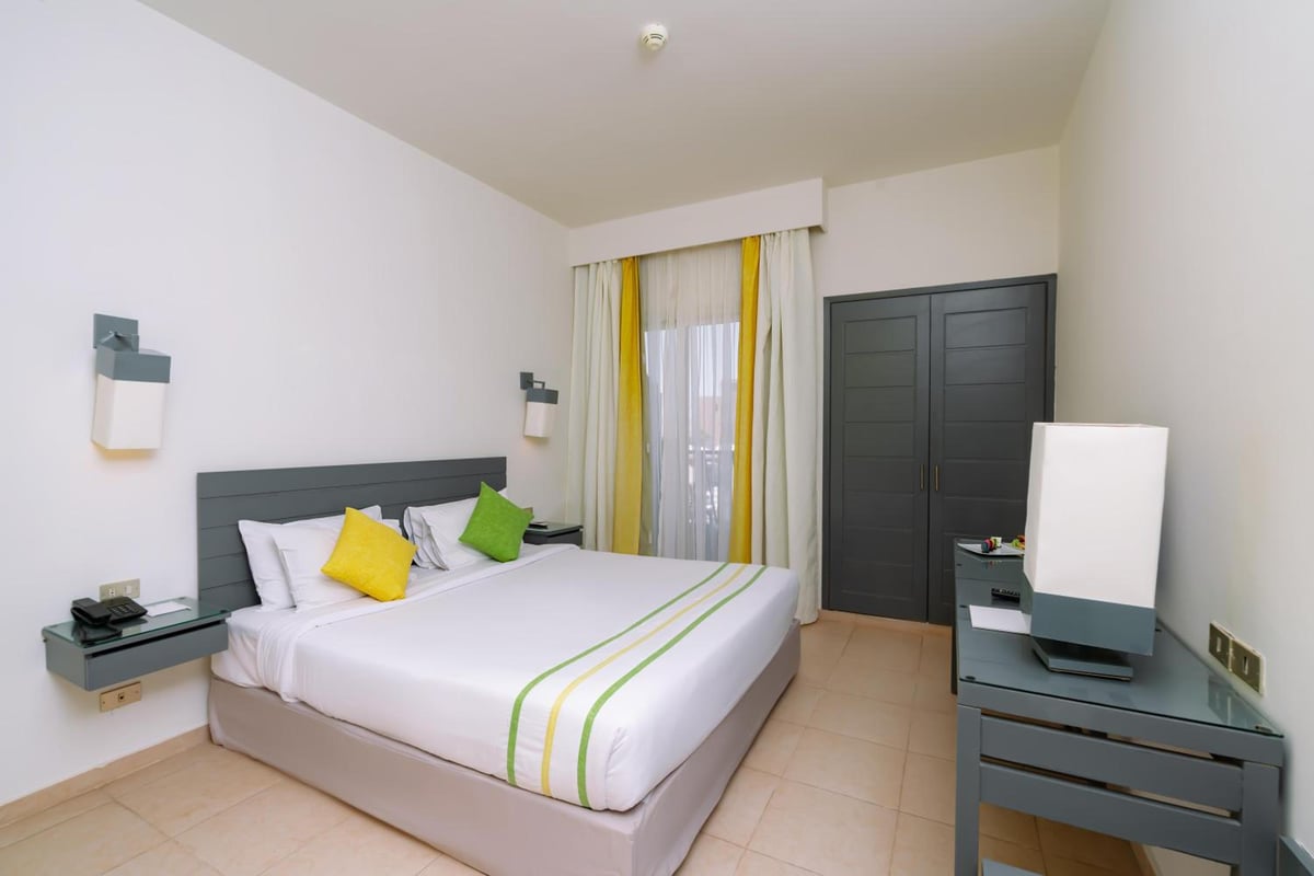 Lemon & Soul Makadi Garden guest bedroom with a large bed and yellow curtains.