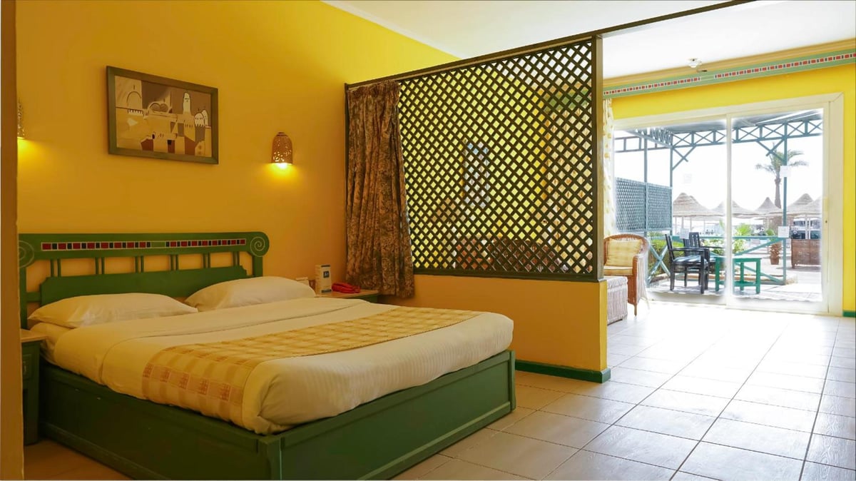 Giftun Azur Resort guest bedroom with a green bed and lattice partition.