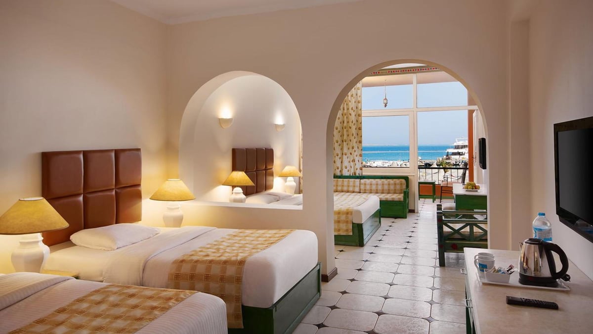 Giftun Azur Resort guest room with twin beds and an arched doorway overlooking the sea.
