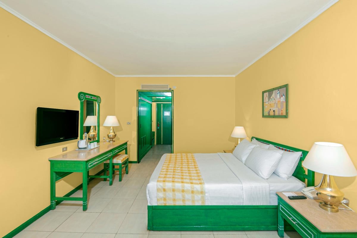 Giftun Azur Resort guest bedroom with a green bed frame and yellow walls.