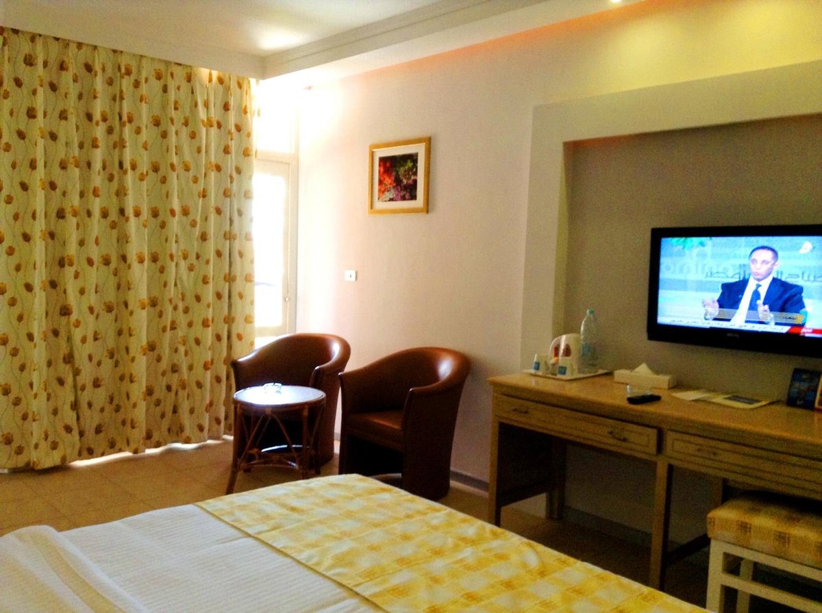 Giftun Azur Resort guest room with a wall-mounted television and two armchairs.