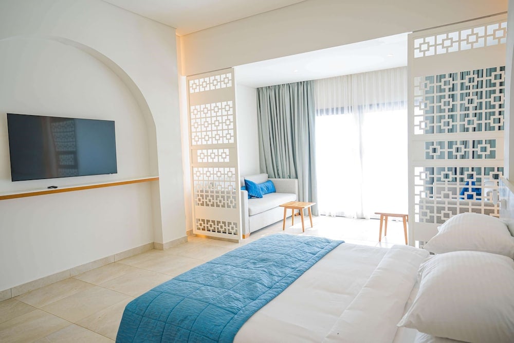 SENTIDO Reef Oasis Suakin Resort guest bedroom with a blue bed runner and geometric screens.