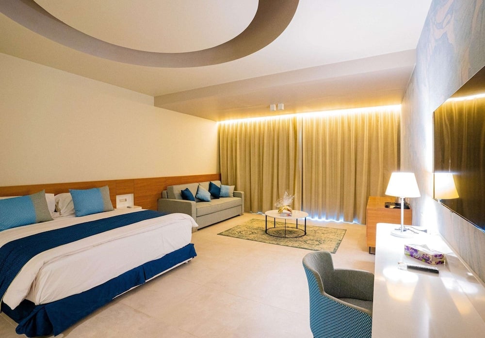 SENTIDO Reef Oasis Suakin Resort bedroom with a large bed and sofa seating.