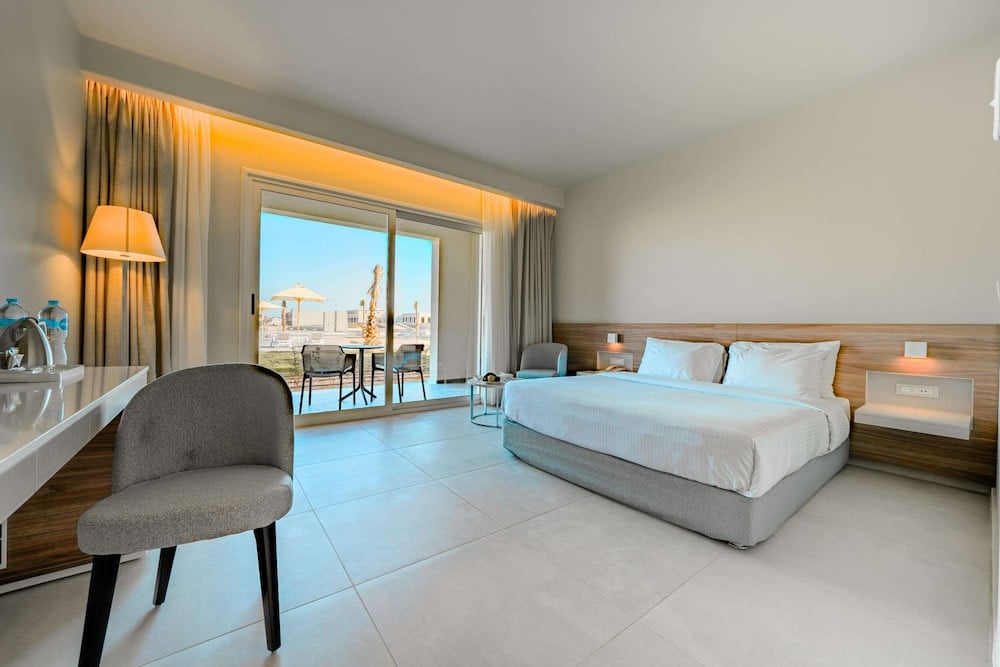 SENTIDO Reef Oasis Suakin Resort bedroom with a bed and sliding glass doors.