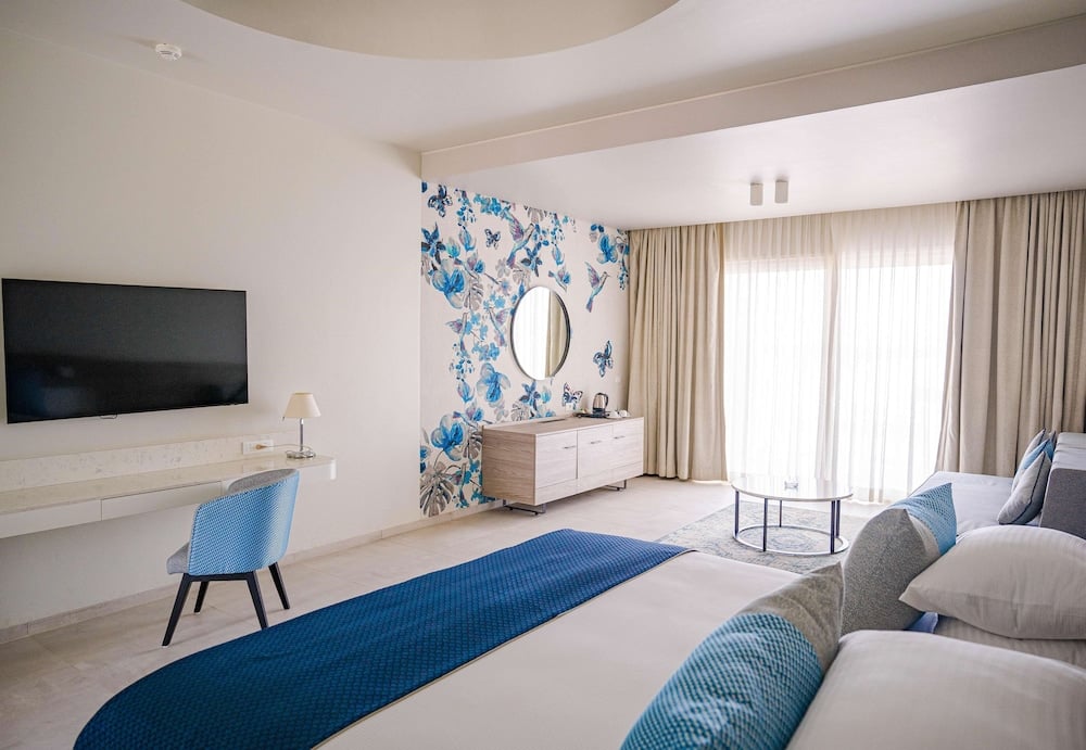 SENTIDO Reef Oasis Suakin Resort guest room with a blue floral wall and seating area.