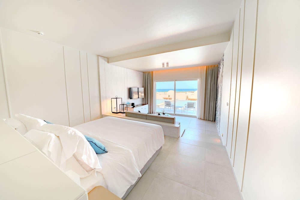 SENTIDO Reef Oasis Suakin Resort guest bedroom with a large bed and sliding glass doors.