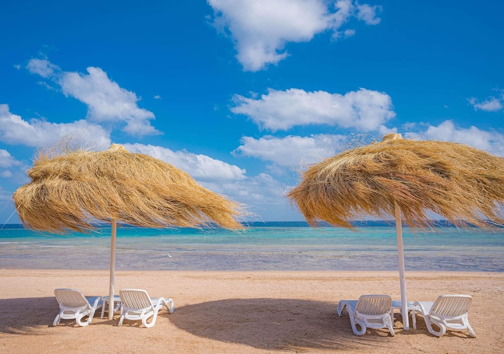 SENTIDO Reef Oasis Suakin Resort beach with thatched parasols and turquoise sea.
