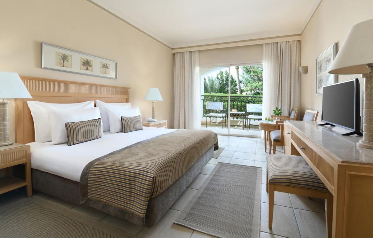 JAZ Makadi Star & Spa (Adults Only) guest bedroom with a large bed and balcony doors.