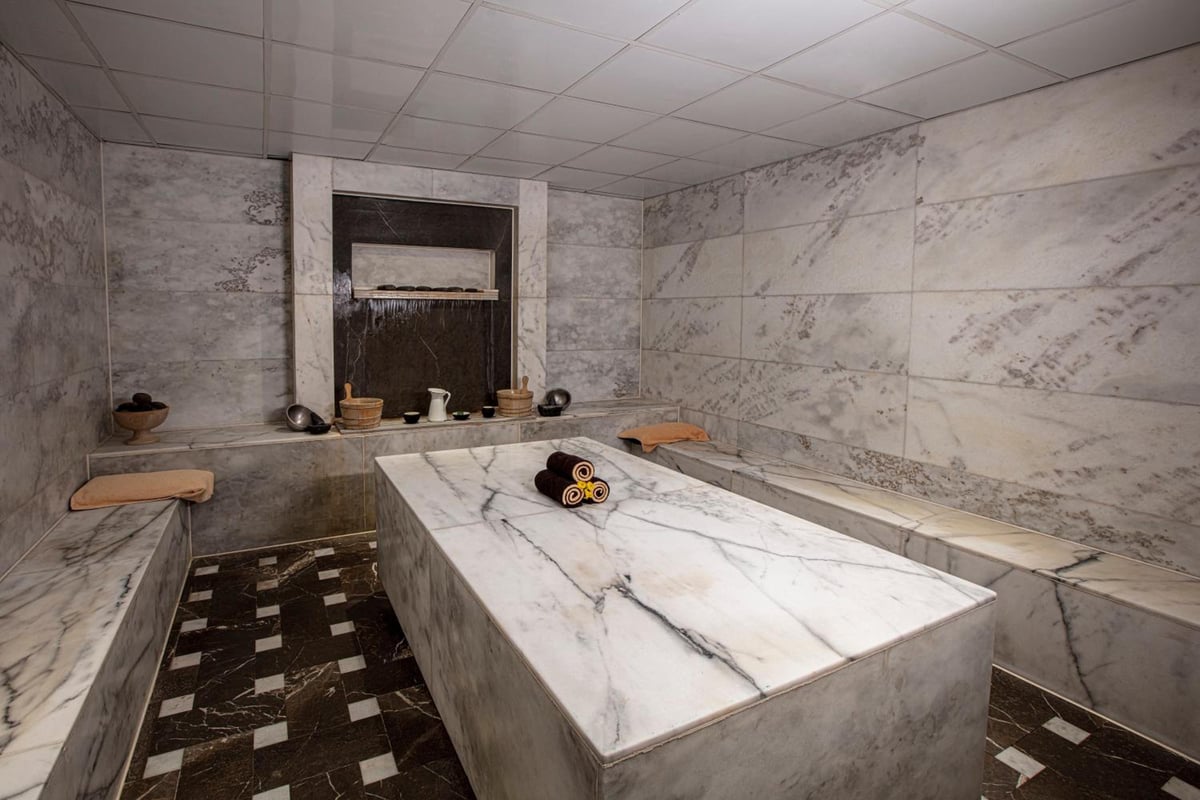 JAZ Makadi Star & Spa (Adults Only) spa treatment room with a marble table and tiled walls.