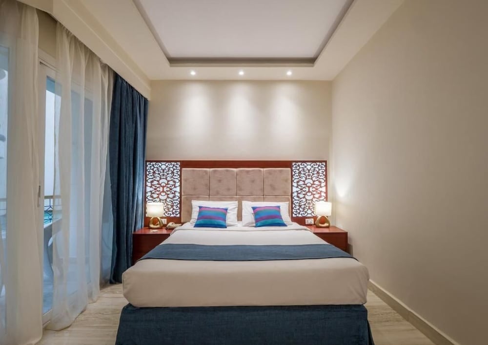 Seagull Beach Resort Hurghada bedroom with decorative headboard panels and balcony access.