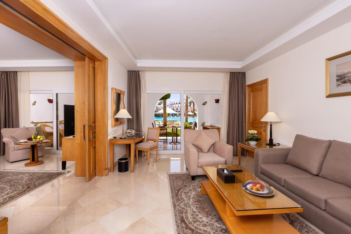 Savoy Sharm El Sheikh suite living room with a sofa and arched balcony doors.