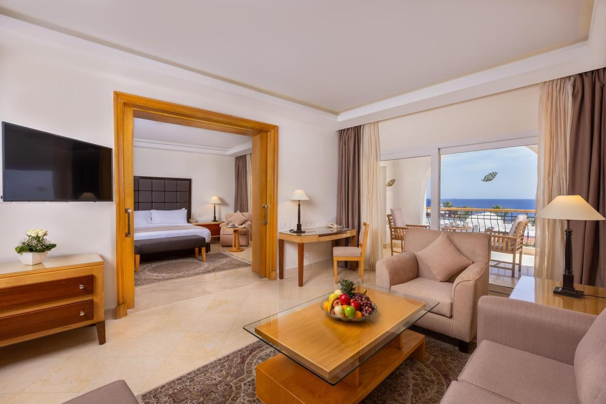 Savoy Sharm El Sheikh suite living room with an adjoining bedroom and a sea-view balcony.