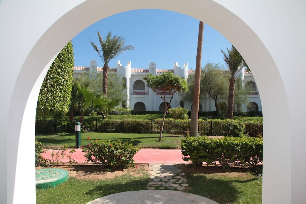Savoy Sharm El Sheikh garden courtyard with a stone path and white arched building.