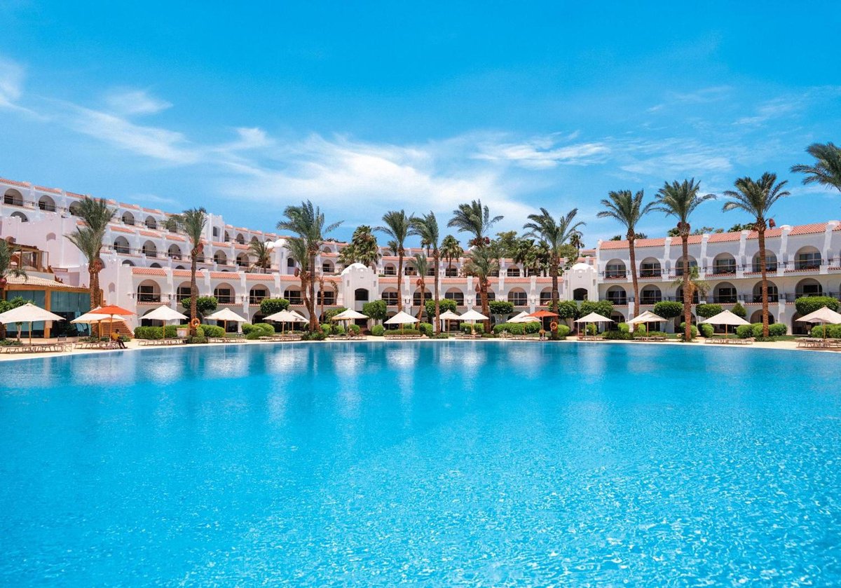 Savoy Sharm El Sheikh pool with turquoise water and palm-lined buildings.