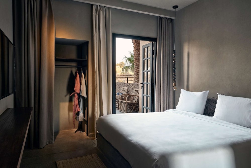 Cook's Club El Gouna (Adults Only) bedroom with a white bed and open balcony doors.