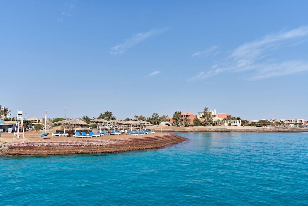 Cook's Club El Gouna beach with thatched umbrellas and turquoise water.